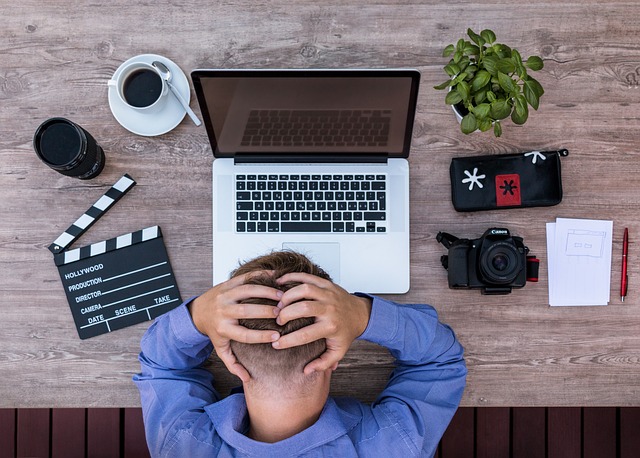 Gestresster Mensch am Computer von oben betrachtet. Business Coaching als Schlüssel zu Sressreduktion, Orientierung und nachhaltigem Erfolg